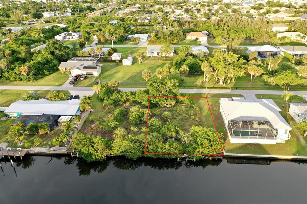 An aerial view shows a vacant, wooded waterfront lot outlined in red between two houses — 3717 WISTERIA PLACE, PUNTA GORDA, FL