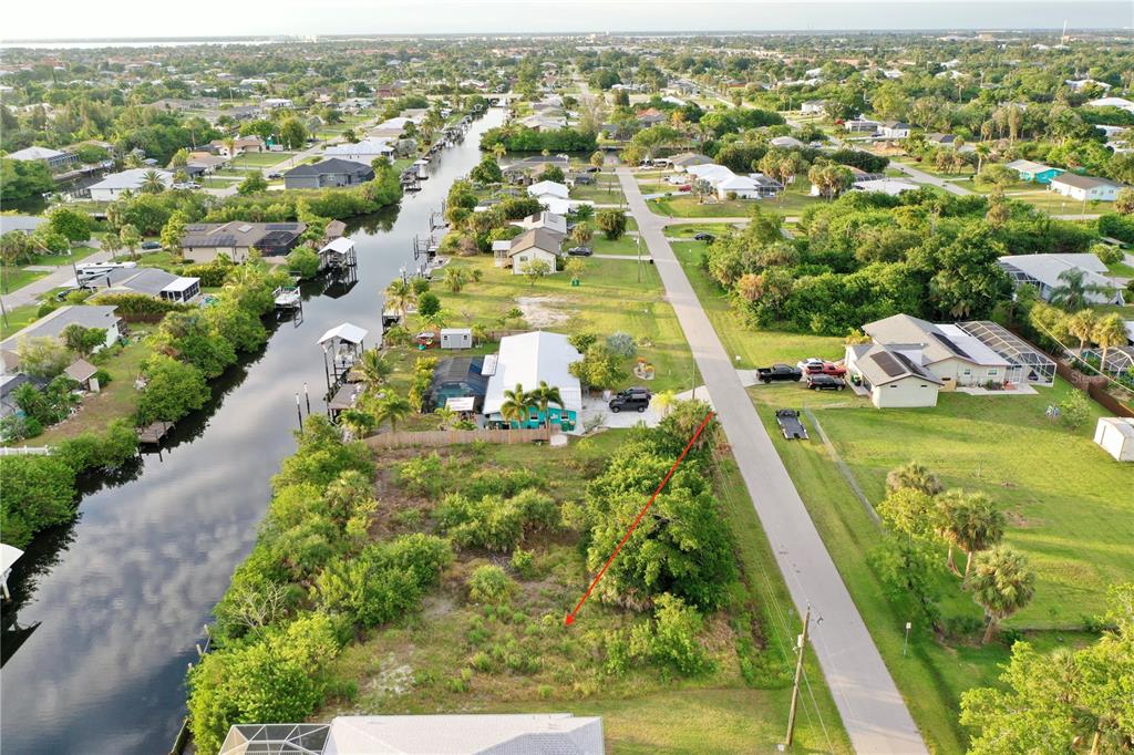 An aerial view shows a vacant, overgrown lot situated between a canal and a road — 3717 WISTERIA PLACE, PUNTA GORDA, FL