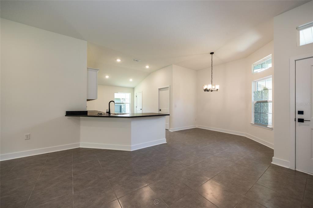 An open-concept dining area features tile flooring, a breakfast bar, and a chandelier — 77 PICKERING DRIVE, PALM COAST, FL