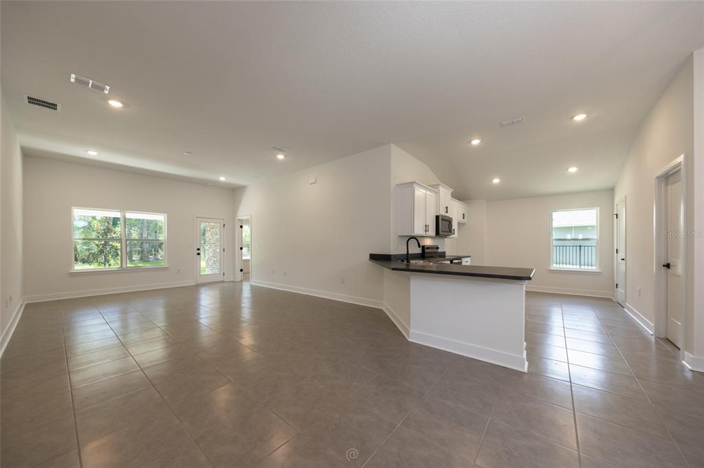 An open-concept living area features a kitchen with a breakfast bar and tile flooring — 77 PICKERING DRIVE, PALM COAST, FL