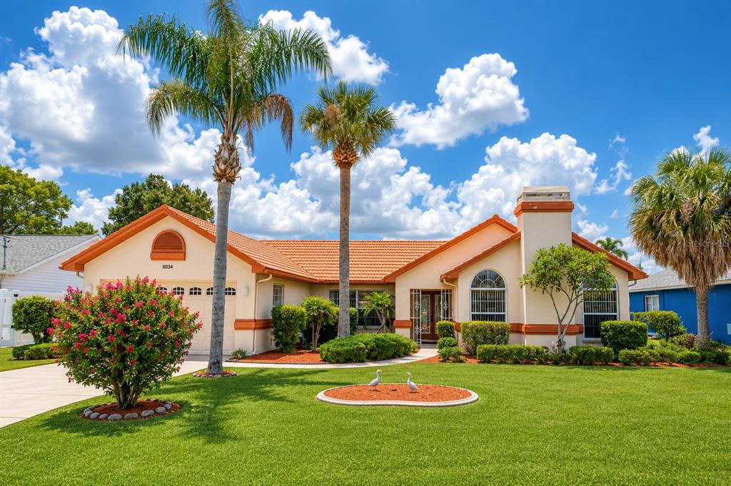 A single-story house with a tile roof, palm trees, and a landscaped front lawn — 11034 AUBURNDALE STREET, SPRING HILL, FL