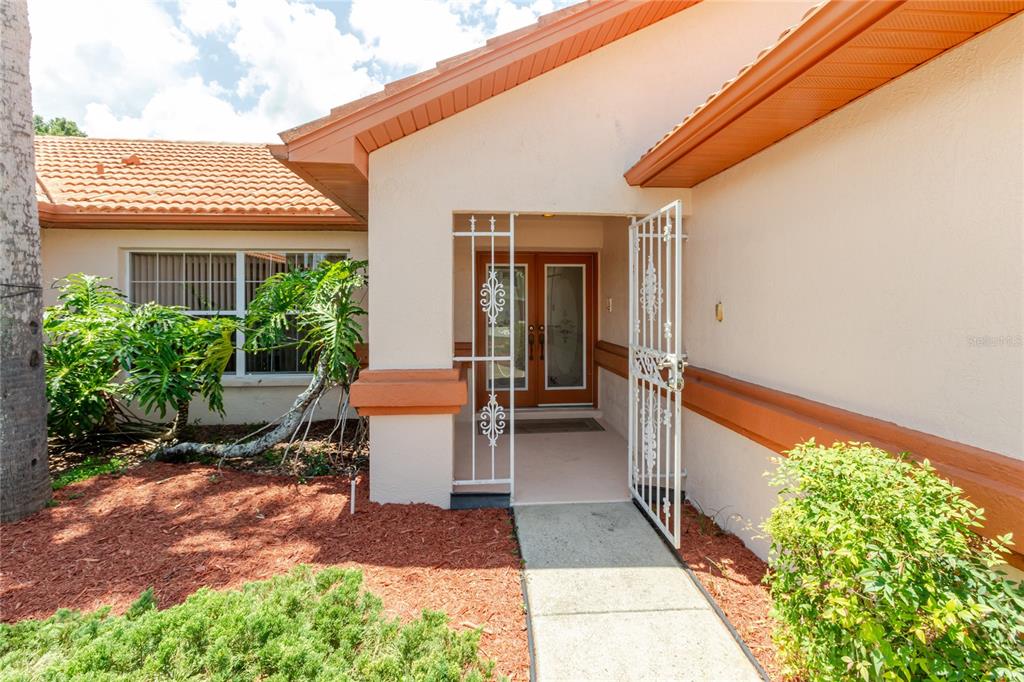 The exterior of a house features a tiled roof, a security gate, and double doors — 11034 AUBURNDALE STREET, SPRING HILL, FL