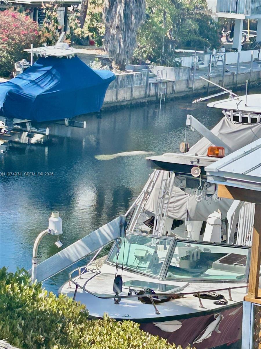 A manatee swims in a canal between two docked boats — 212 Banyan Ln, Tavernier FL 33070, TAVERNIER, FL