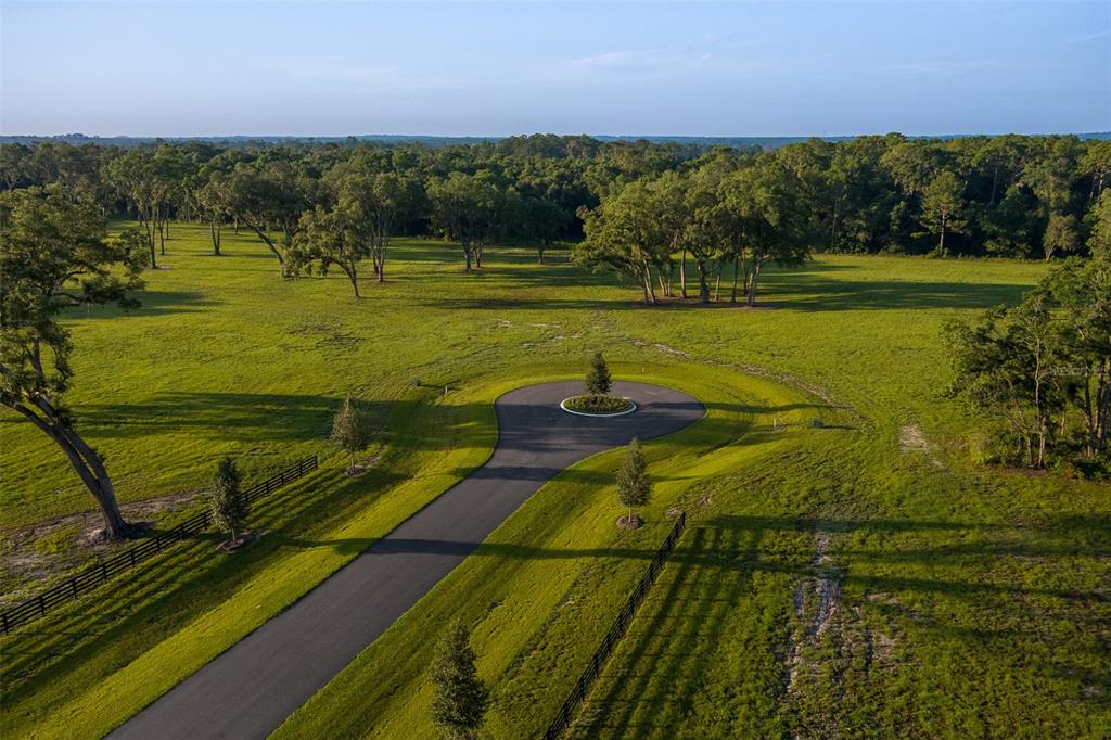 An aerial view shows a paved cul-de-sac surrounded by a large, grassy field with trees — 11771 NW 50TH LANE ROAD, OCALA, FL