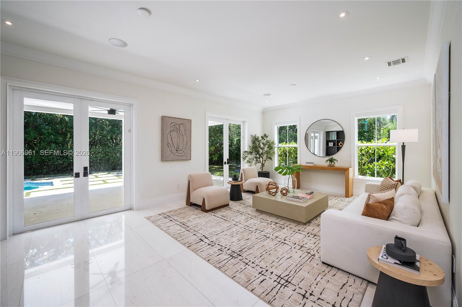 A bright living room features white tile floors, a neutral area rug, and glass doors — 680 Destacada Ave, Coral Gables FL 33156, CORAL GABLES, FL