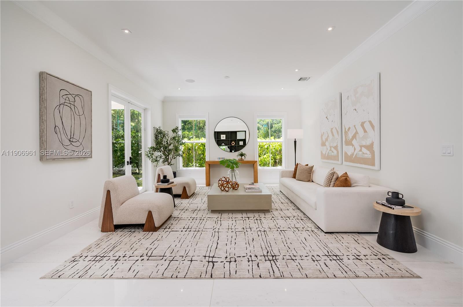 A bright, modern living room features white walls, a patterned area rug, and neutral furniture — 680 Destacada Ave, Coral Gables FL 33156, CORAL GABLES, FL