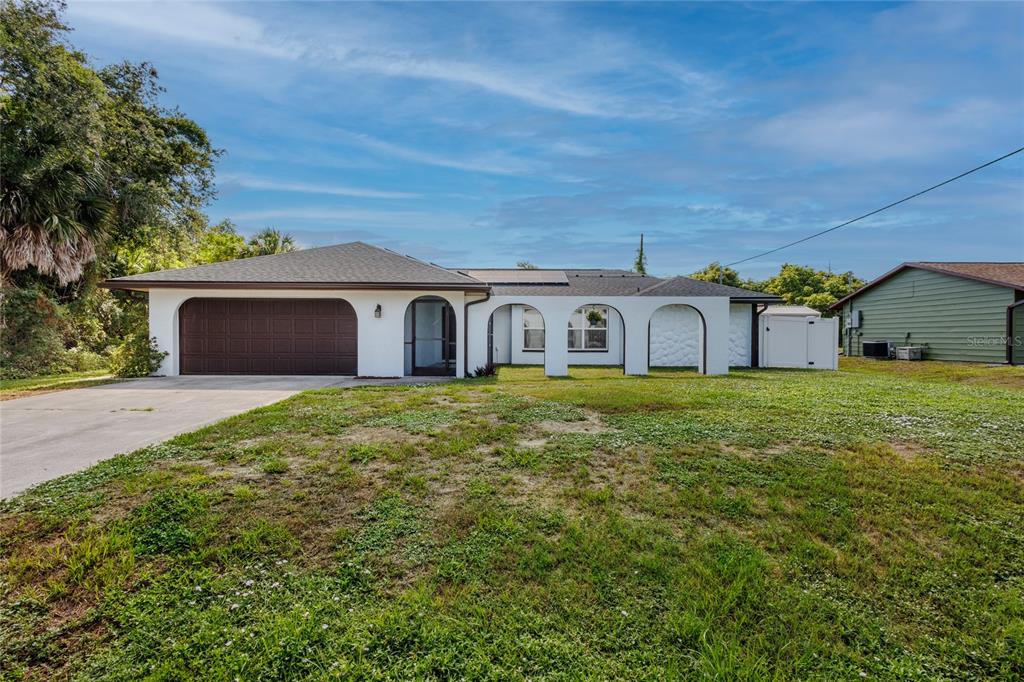 A single-story house with a white exterior, arched entryway, and attached garage sits on a lawn — 2772 AUBURN BOULEVARD, PORT CHARLOTTE, FL