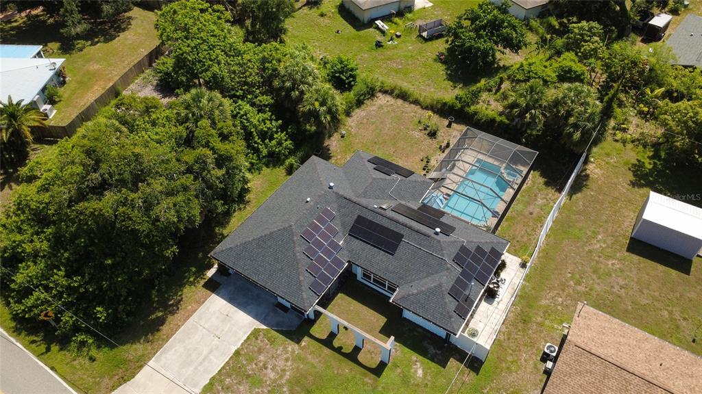 An aerial view shows a house with solar panels, a pool enclosure, and a large yard — 2772 AUBURN BOULEVARD, PORT CHARLOTTE, FL