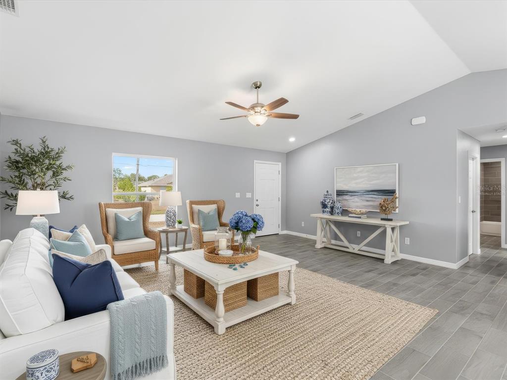 A living room features gray walls, tile flooring, a white sofa, and two wicker armchairs — 12081 SNOW BIRD AVENUE, PORT CHARLOTTE, FL