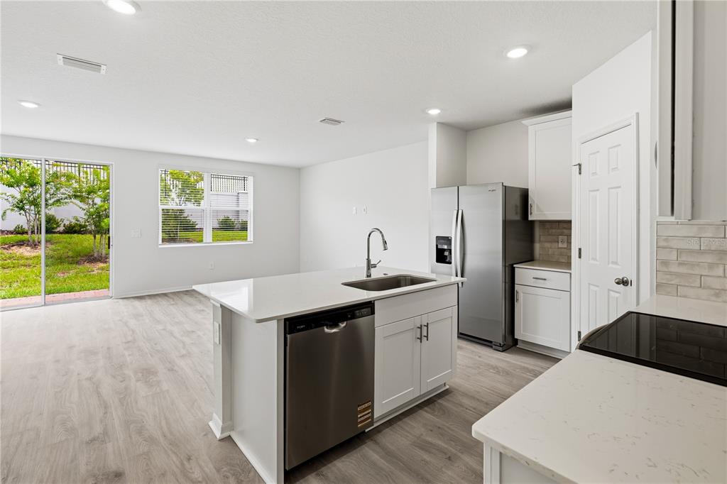 A kitchen with a center island, stainless steel appliances, and light wood-look flooring — 16278 BIRD OF PARADISE AVENUE, CLERMONT, FL