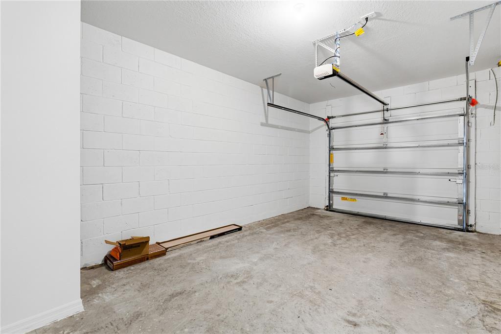 An empty garage with white concrete block walls, a concrete floor, and a metal door — 16278 BIRD OF PARADISE AVENUE, CLERMONT, FL
