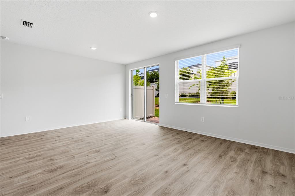 An empty room features light wood-look flooring, white walls, recessed lighting, and a sliding door — 16278 BIRD OF PARADISE AVENUE, CLERMONT, FL