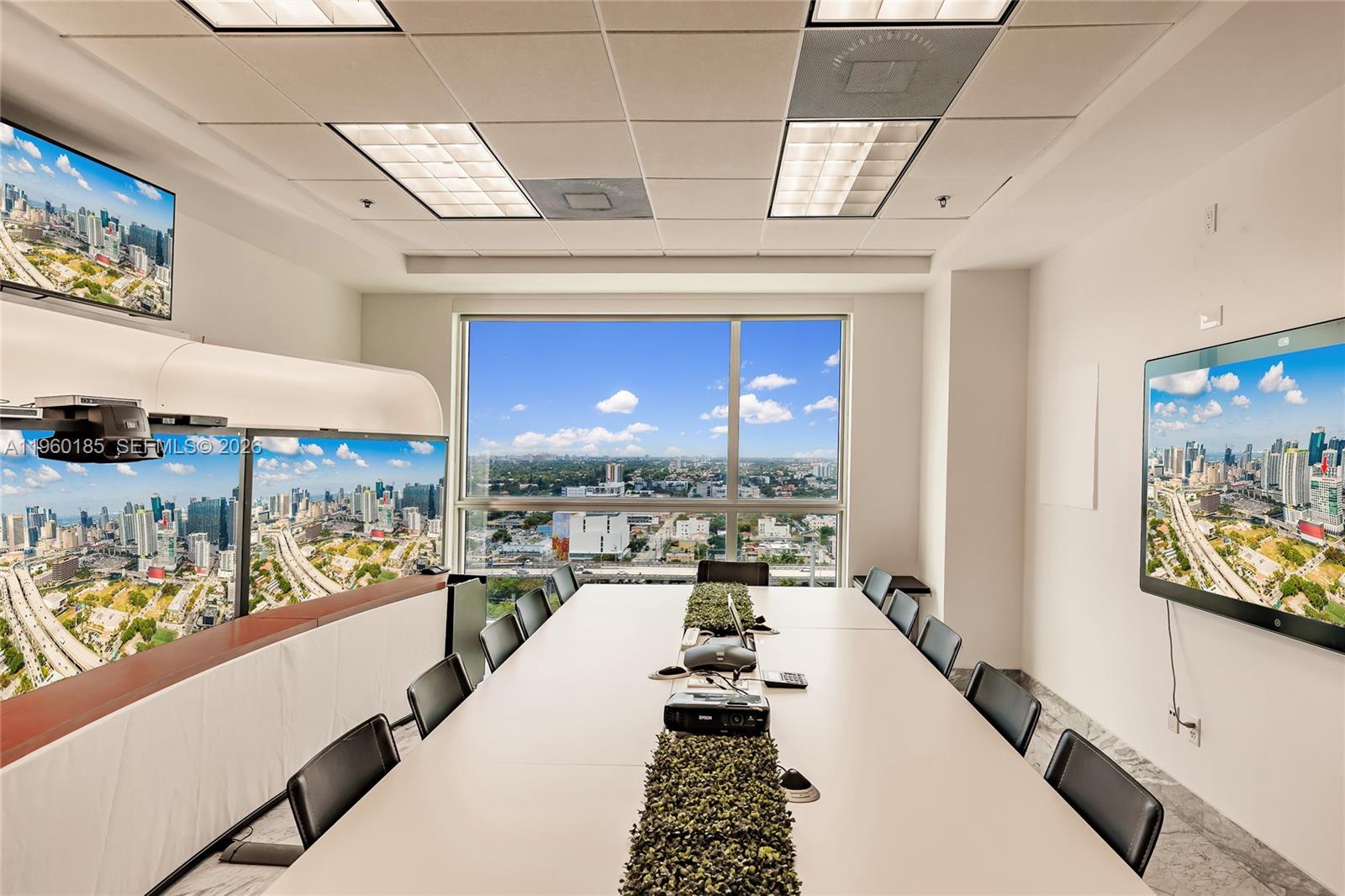 A conference room features a long table, chairs, wall-mounted screens, and a city view — 175 SW 7th St # 1901, Miami FL 33130, MIAMI, FL