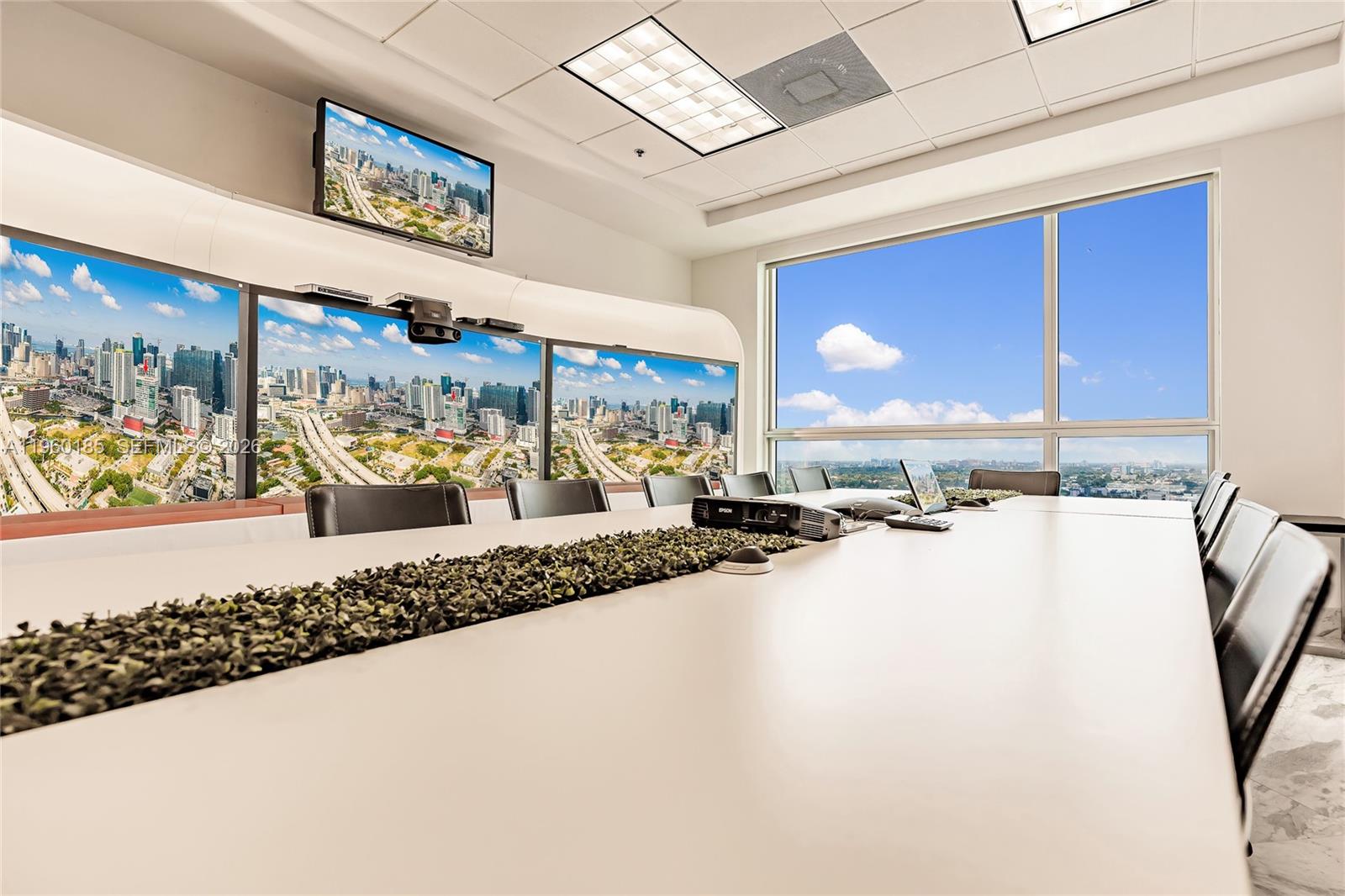 A modern conference room features a long table, multiple wall-mounted screens, and large windows — 175 SW 7th St # 1901, Miami FL 33130, MIAMI, FL