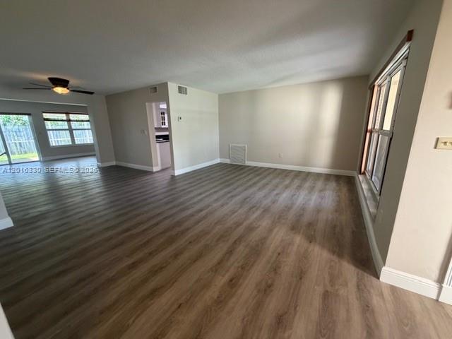 An open-concept living area features light wood-look flooring, a ceiling fan, and large windows — 10524 NW 4th St, Plantation FL 33324, PLANTATION, FL