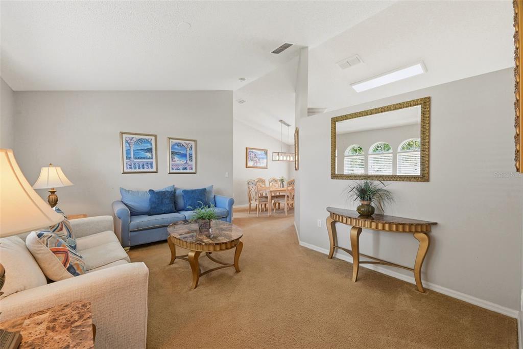 A living room with beige carpet, a blue sofa, a console table, and a dining area — 143 WHITEHALL STREET, DAVENPORT, FL