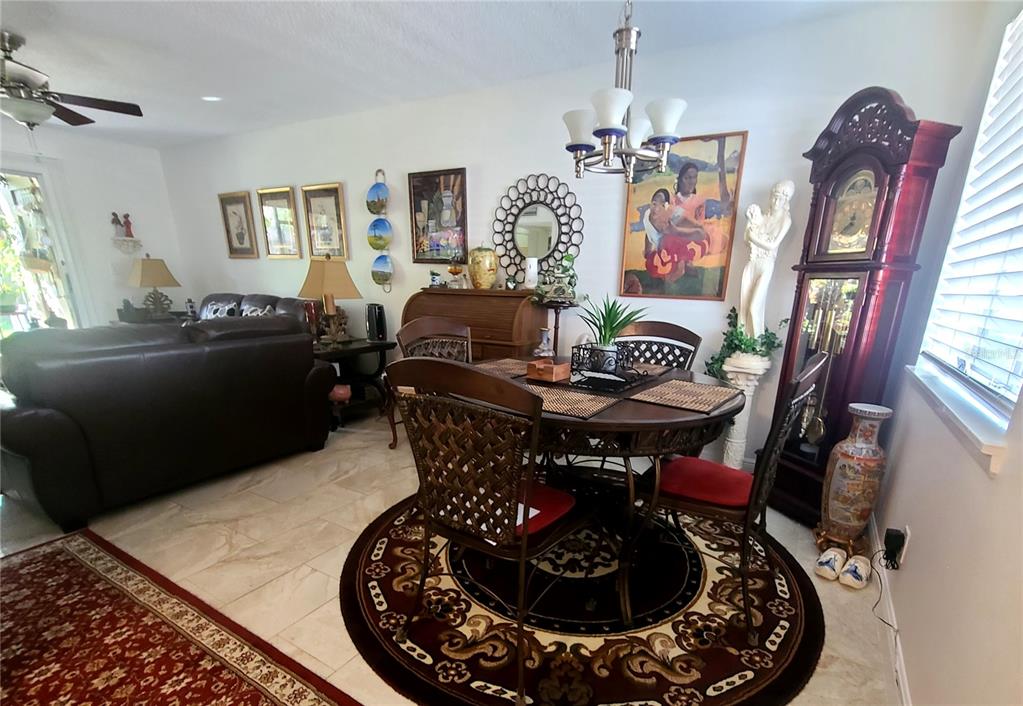A dining area with a round table and chairs sits adjacent to a living room — 6328 NEWTOWN CIRCLE UNIT 28A2, TAMPA, FL