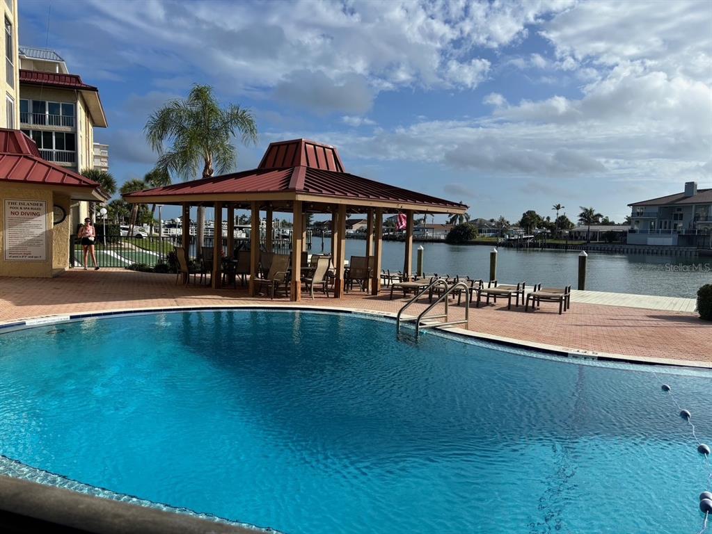 A swimming pool sits in front of a covered pavilion beside a canal — 121 ISLAND WAY UNIT 331, CLEARWATER BEACH, FL