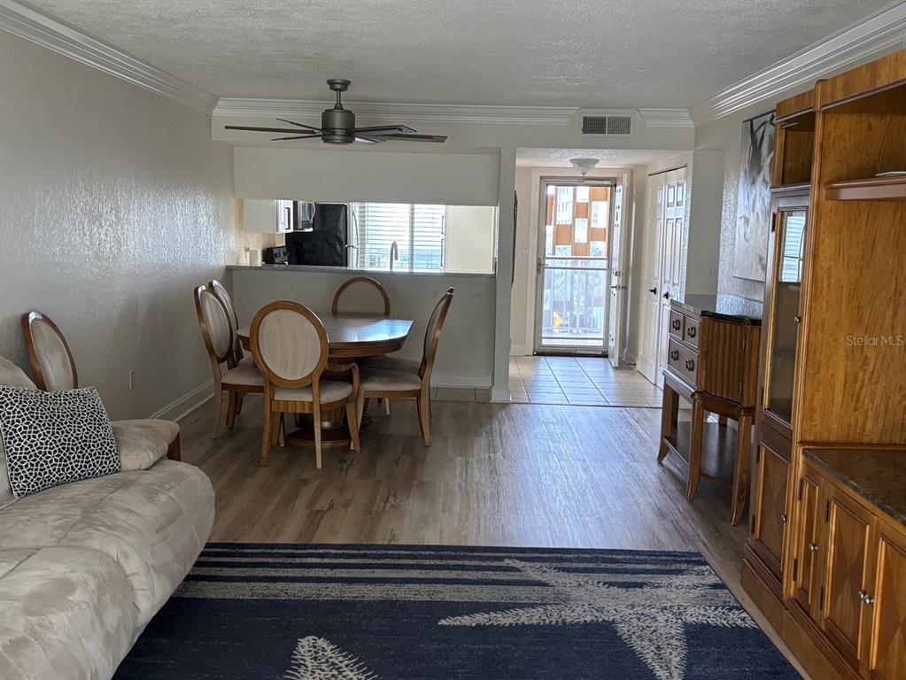 A living and dining area with wood-look flooring, a ceiling fan, and a kitchen pass-through — 121 ISLAND WAY UNIT 331, CLEARWATER BEACH, FL