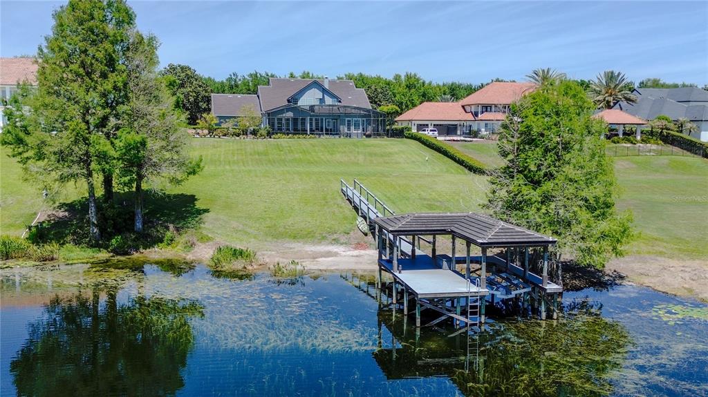An aerial view shows a house with a dock extending into a lake — 9648 WEATHERSTONE COURT, WINDERMERE, FL
