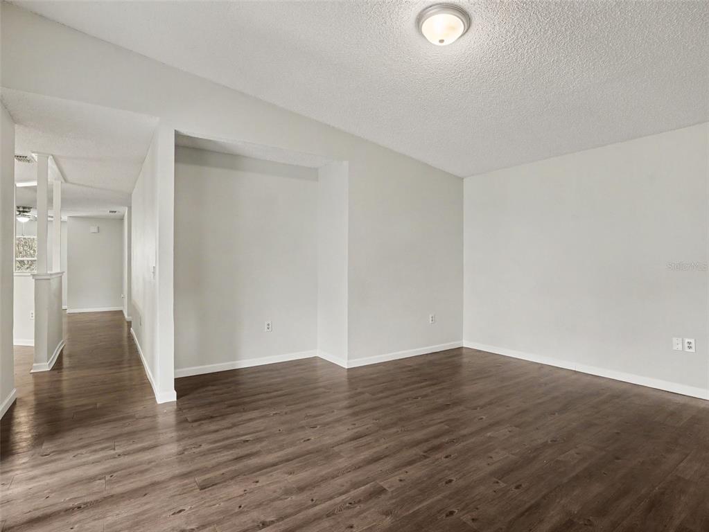 An empty room with light gray walls, dark wood-look flooring, and a recessed wall area — 406 LAKE DAISY DRIVE, WINTER HAVEN, FL