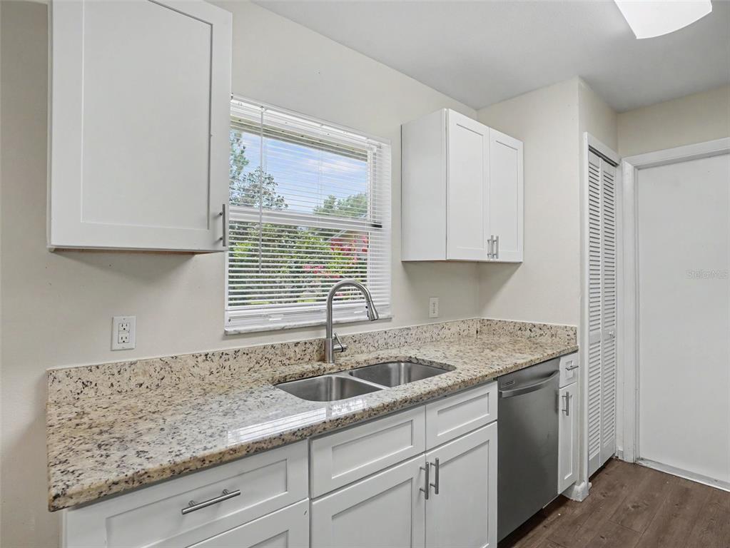 A kitchen features white cabinets, granite countertops, a stainless steel sink, and a dishwasher — 406 LAKE DAISY DRIVE, WINTER HAVEN, FL