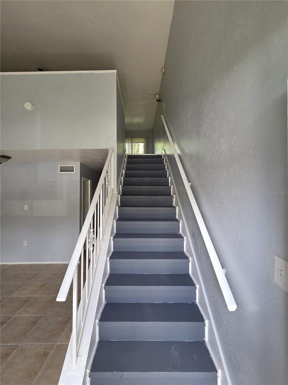 A staircase with gray treads and white railings leads to an upper landing — 3976 CRAYRICH CIRCLE UNIT C1, ORLANDO, FL