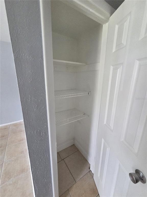 A small closet with two wire shelves and a white door stands in a tiled room — 3976 CRAYRICH CIRCLE UNIT C1, ORLANDO, FL
