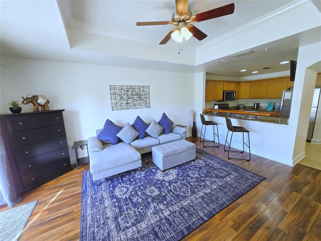 A living room features a sectional sofa, a large blue rug, and an open kitchen — 1322 SEVEN EAGLES COURT UNIT 102, REUNION, FL