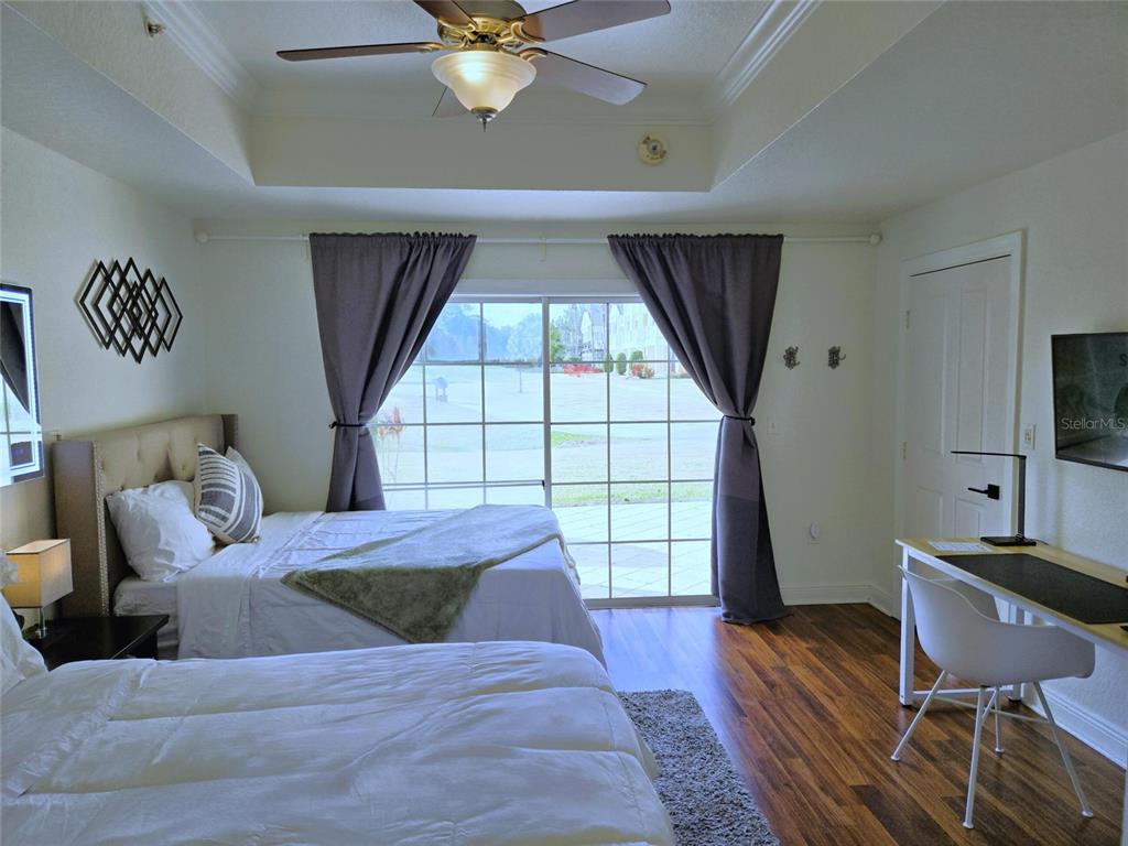 A bedroom features two beds, a desk, a ceiling fan, and sliding glass doors — 1322 SEVEN EAGLES COURT UNIT 102, REUNION, FL
