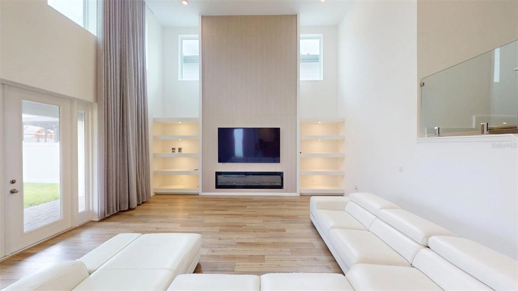 A living room features a tall fireplace wall with built-in shelves and light wood flooring — 17242 LAKE STAR ROAD, WINTER GARDEN, FL