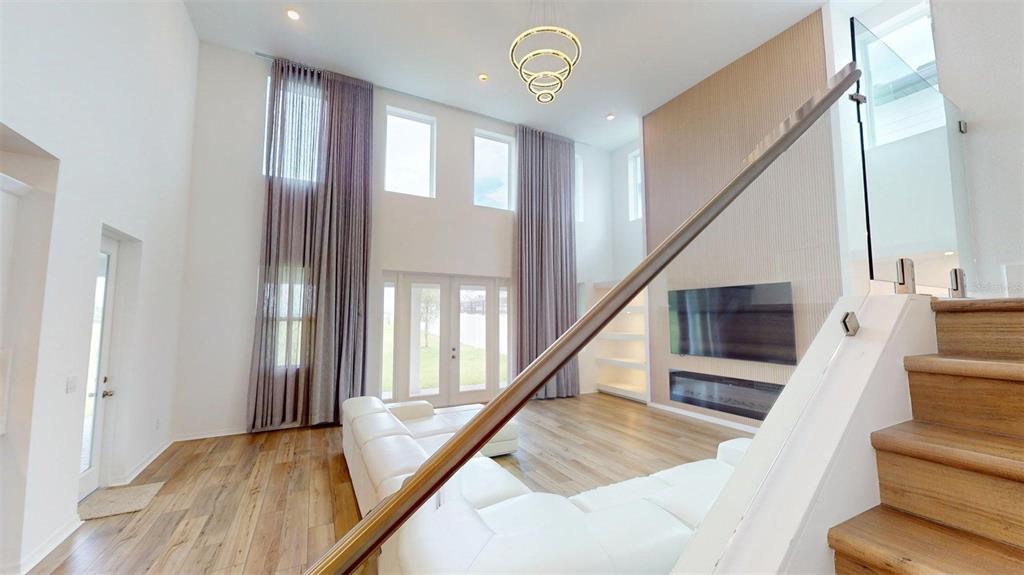A spacious living room features a large white sectional sofa, light wood flooring, and stairs — 17242 LAKE STAR ROAD, WINTER GARDEN, FL