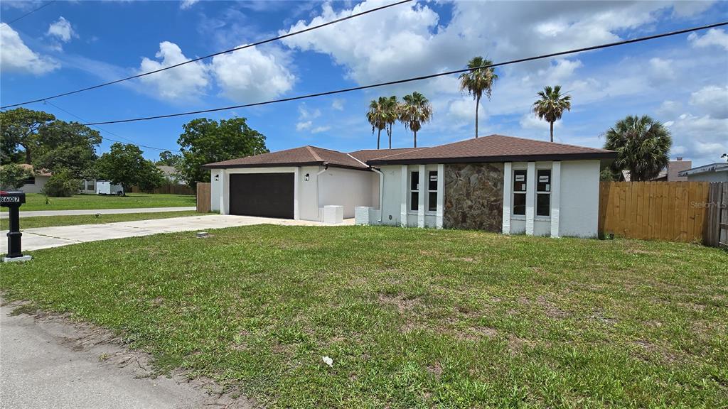 A single-story house with a white exterior, stone accent wall, and attached two-car garage — 8607 LONGBOAT LANE, HUDSON, FL