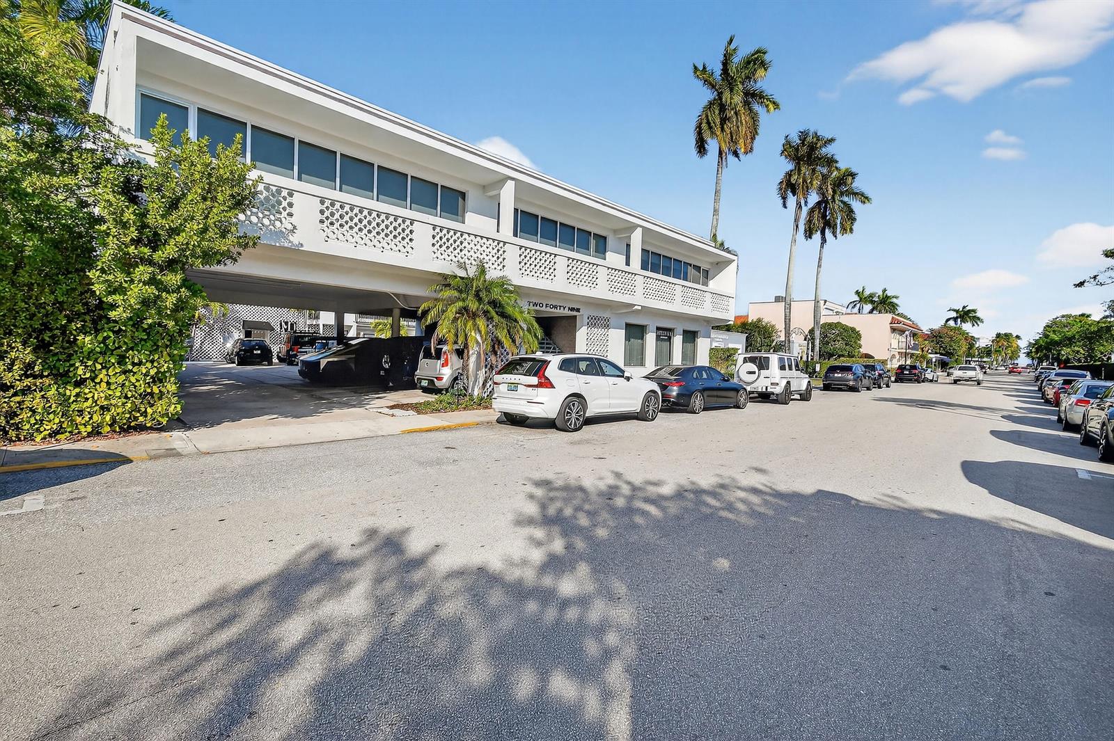 A white two-story commercial building with covered parking and palm trees on a sunny street — 249 Peruvian Avenue # 1811, Palm Beach FL 33480, PALM BEACH, FL