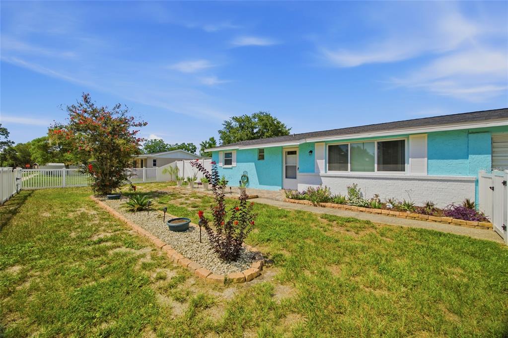 A turquoise house with a white trim and a gravel garden bed in the yard — 9347 MIRACLE DRIVE, SPRING HILL, FL