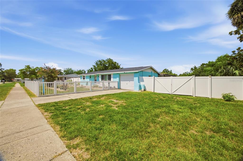 A light blue house with a white garage door and a white vinyl privacy fence — 9347 MIRACLE DRIVE, SPRING HILL, FL