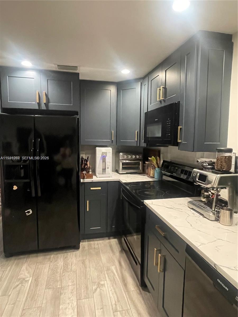 A kitchen features dark blue cabinets, black appliances, and white countertops with grey veining — 2730 Adams St, Hollywood FL 33020, HOLLYWOOD, FL
