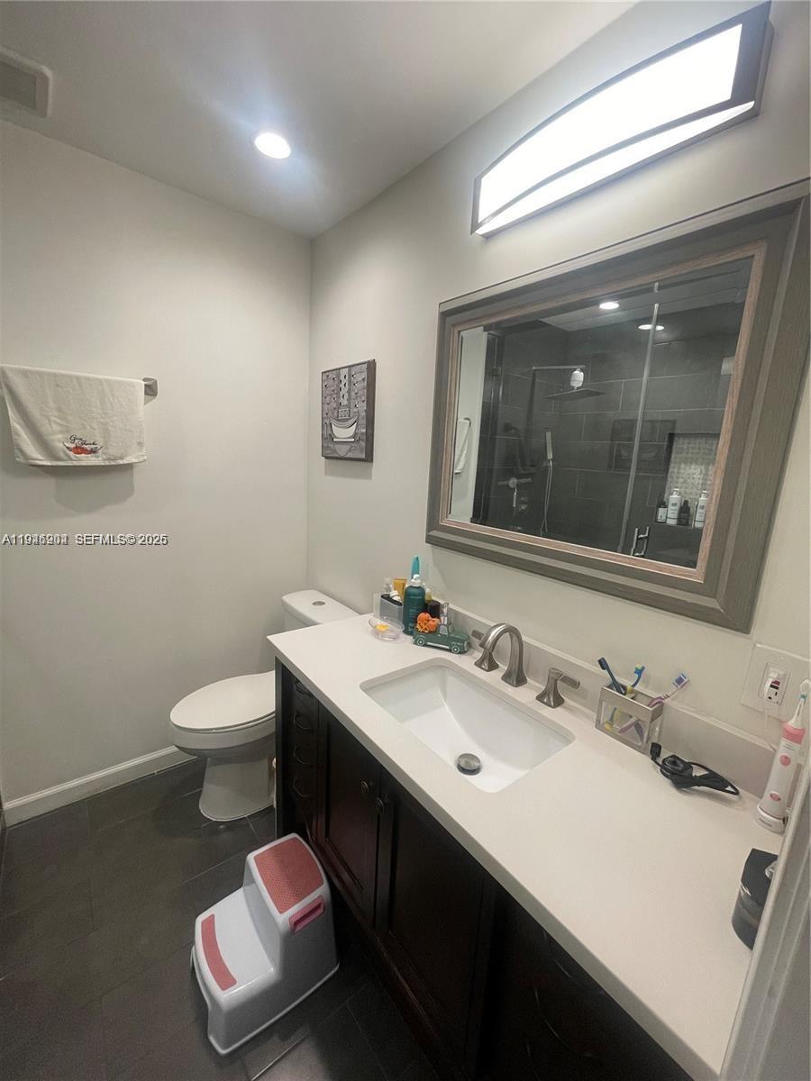 A bathroom features a dark wood vanity, white countertop, rectangular mirror, and a walk-in shower — 2730 Adams St, Hollywood FL 33020, HOLLYWOOD, FL
