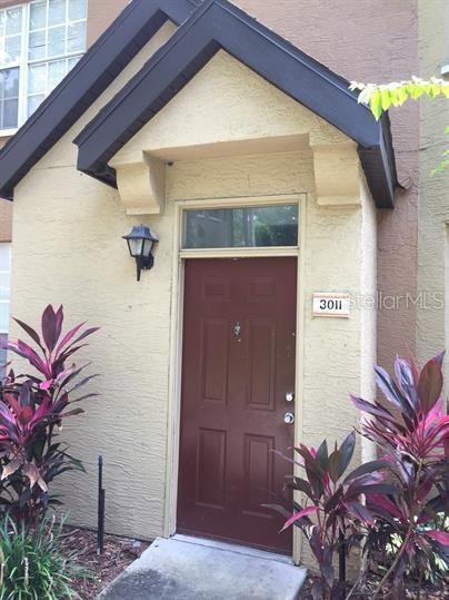 The exterior entrance features a red door, a dark peaked roof, and two potted plants — 6400 RALEIGH STREET UNIT 3011, ORLANDO, FL
