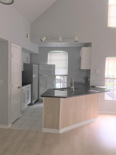 A kitchen with light wood cabinets, a dark countertop island, and white tile flooring — 6400 RALEIGH STREET UNIT 3011, ORLANDO, FL