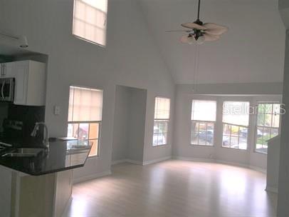 A kitchen with dark countertops opens into a bright living area with vaulted ceilings — 6400 RALEIGH STREET UNIT 3011, ORLANDO, FL