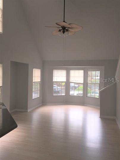 An empty living room with light wood flooring, a vaulted ceiling, and a bay window — 6400 RALEIGH STREET UNIT 3011, ORLANDO, FL