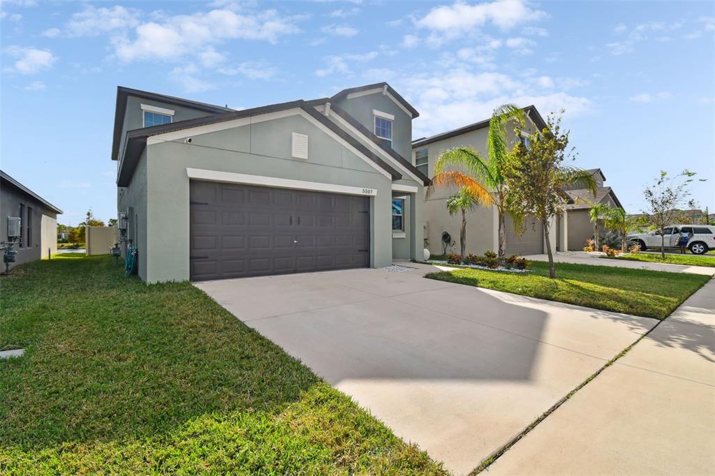 A two-story suburban house with a gray stucco exterior and a two-car garage — 5507 RAINWOOD MEADOWS DRIVE, APOLLO BEACH, FL