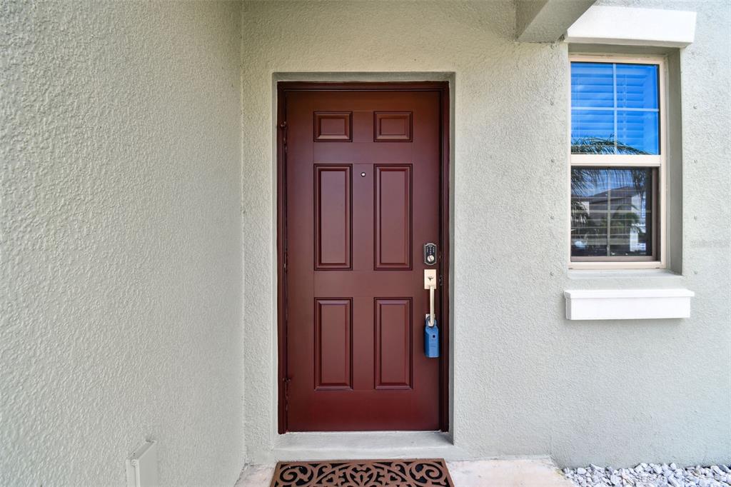 A red front door with a keypad lock and a window on a stucco exterior — 5507 RAINWOOD MEADOWS DRIVE, APOLLO BEACH, FL