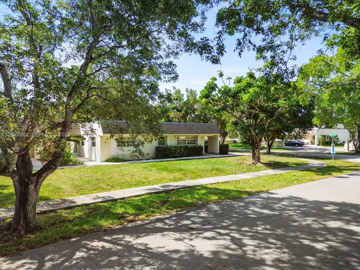 A single-story house with a light-colored exterior sits behind a lawn and mature trees — 17244 SW 112th Pl # 21342, Miami FL 33157, MIAMI, FL