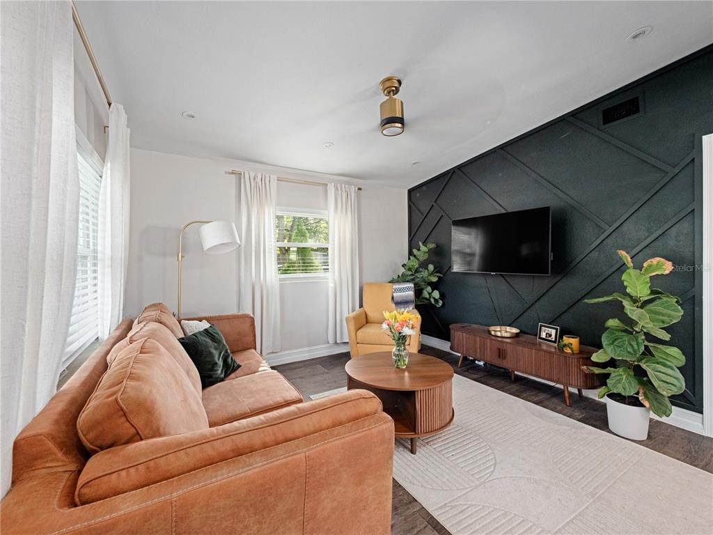 A living room features a brown sofa, a yellow armchair, and a black accent wall — 106 E JINKINS CIRCLE, SANFORD, FL