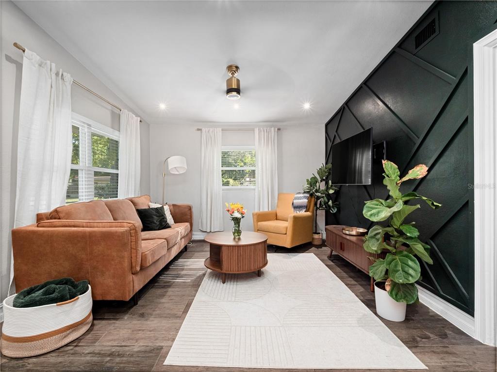 A living room features a brown sofa, yellow armchair, and a dark accent wall — 106 E JINKINS CIRCLE, SANFORD, FL
