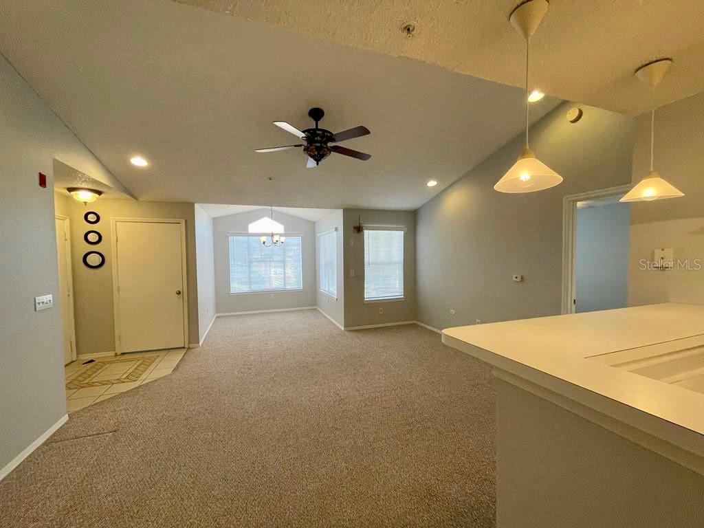 A carpeted living room features a vaulted ceiling, a ceiling fan, and pendant lighting — 2212 GRAND CAYMAN COURT UNIT 1633, KISSIMMEE, FL