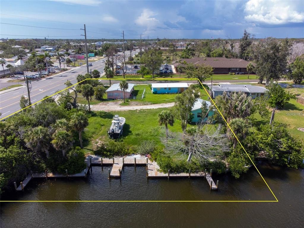 An aerial view shows three small houses on a waterfront lot with a boat dock — 1695 MANOR ROAD, ENGLEWOOD, FL