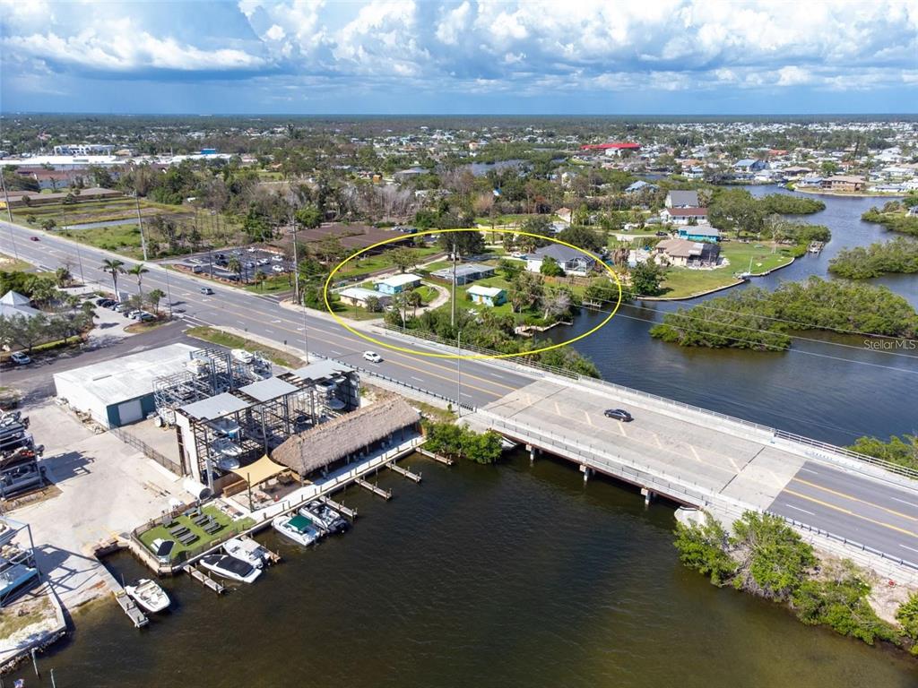 An aerial view shows a waterfront property with several small buildings circled in yellow — 1695 MANOR ROAD, ENGLEWOOD, FL